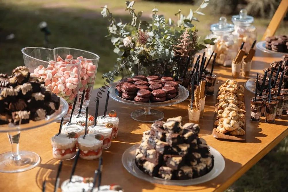 Mesa dulce al aire libre con brownies, vasitos y bandejas de dulces